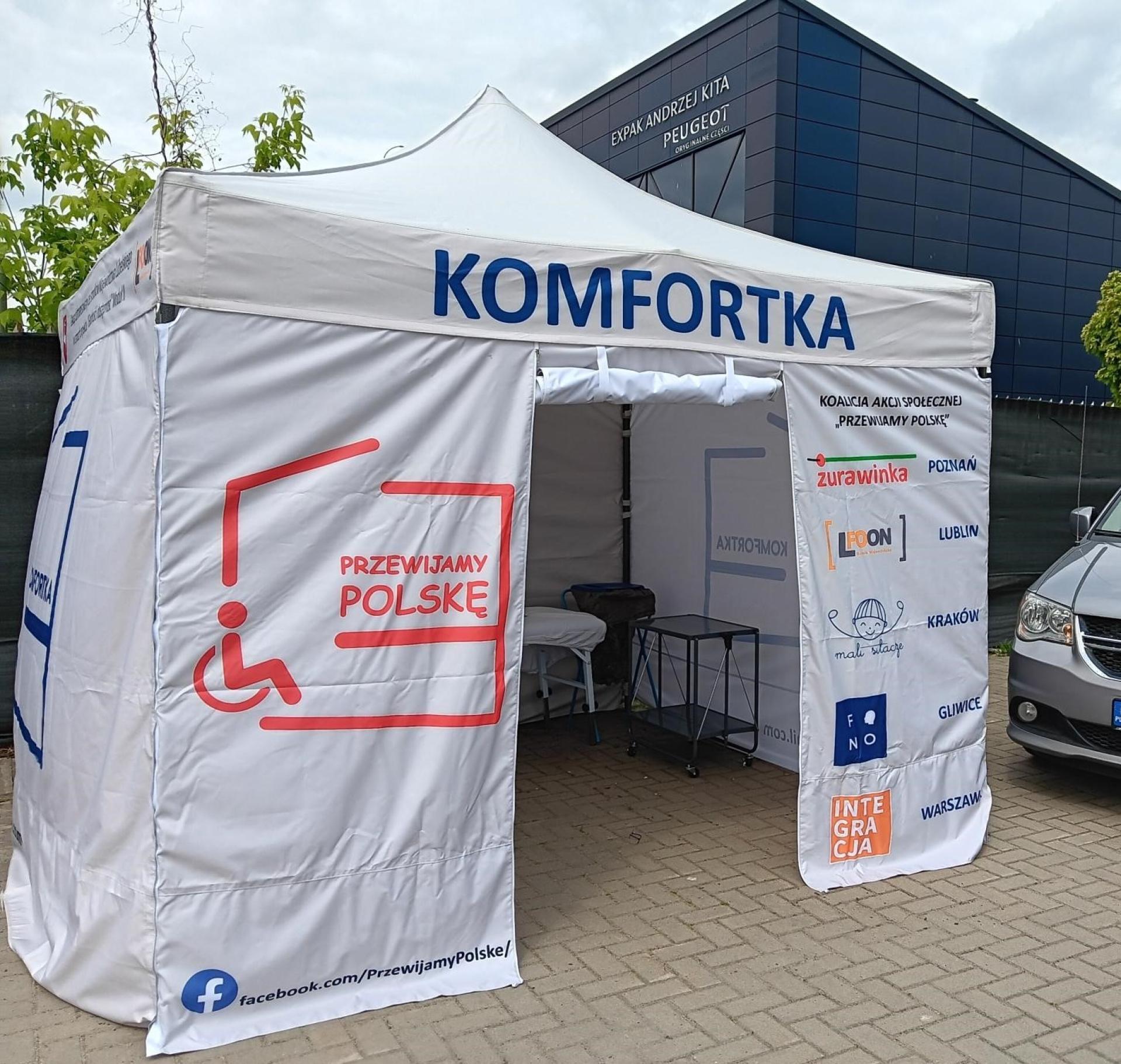 KOMFORTKA plenerowa w posiadaniu LFOON-SW, Namiot z 4 ściankami o logotypami, wewnątrz leżanka, podnośnik, krzesło, kosz na odpady, ogrodowa umywalka i materiały sanitarno-higieniczne